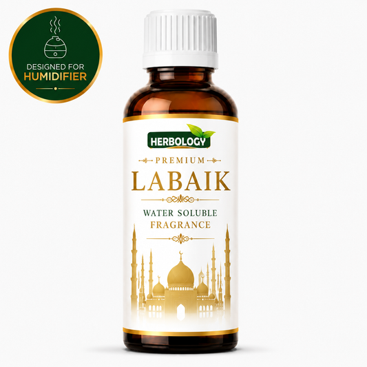 A bottle of Herbology Labaik Premium Water Soluble Fragrance, featuring an amber glass bottle with a white cap and a white label with gold and green accents. A green circular badge in the top-left corner reads 'DESIGNED FOR HUMIDIFIER'.