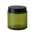 Green glass jar with a black lid on a white background