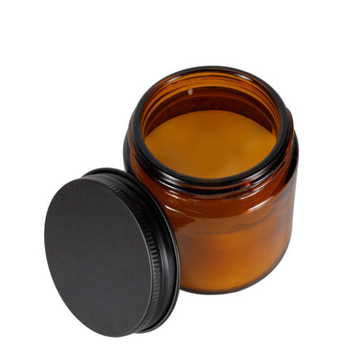 Amber glass jar with black lid on a white background