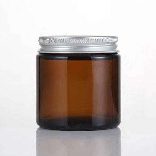 Amber glass jar with silver lid on a white background