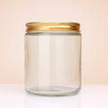 Transparent Glass jar with a gold lid on a light beige background