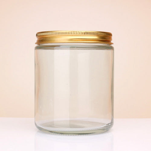 Transparent Glass jar with a gold lid on a light beige background