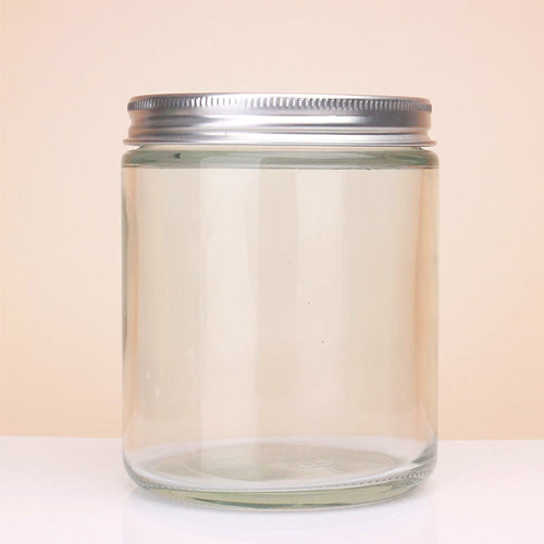 Clear glass jar with a metal lid on a light beige background